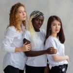 group of diverse women hugging together against gray wall
